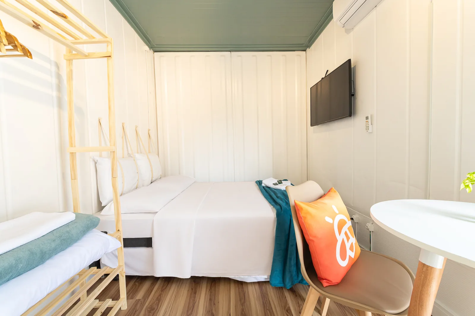 Box no andar térreo: cama de casal, TV, ar-condicionado e mesa num só ambiente